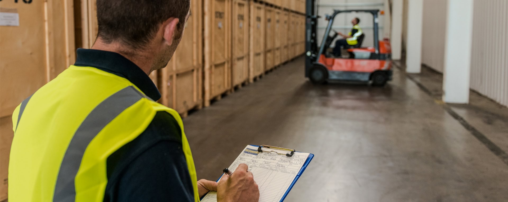 Warehouse team member completing an inventory checklist beside wooden storage crates at Kerr’s of Edinburgh