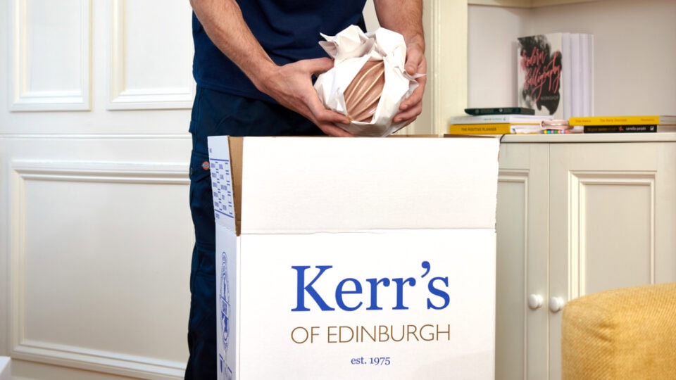 Packing a fragile antique item into a Kerr’s Removals box for secure transport
